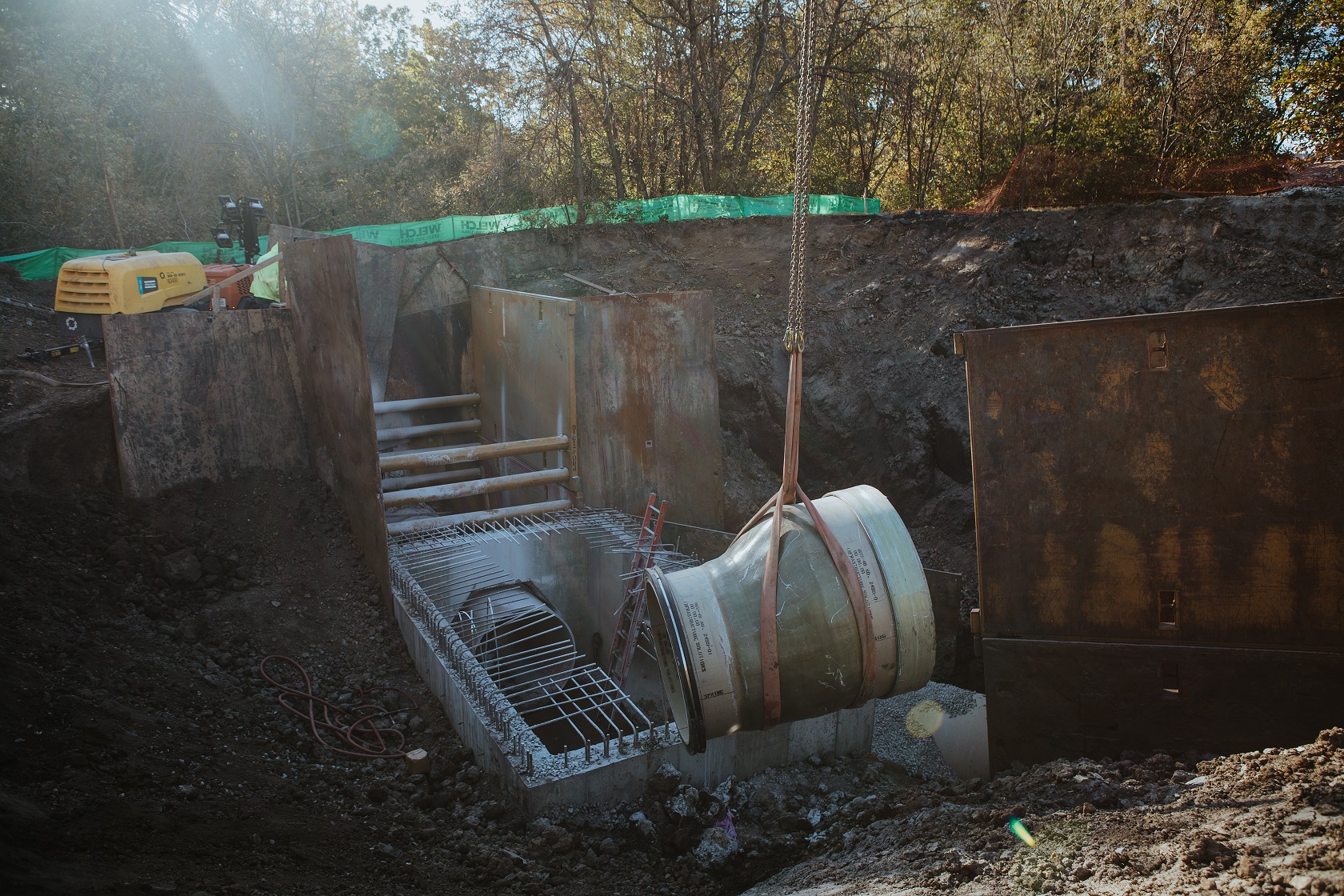 Replacing an underground pipe using a crane and chain.