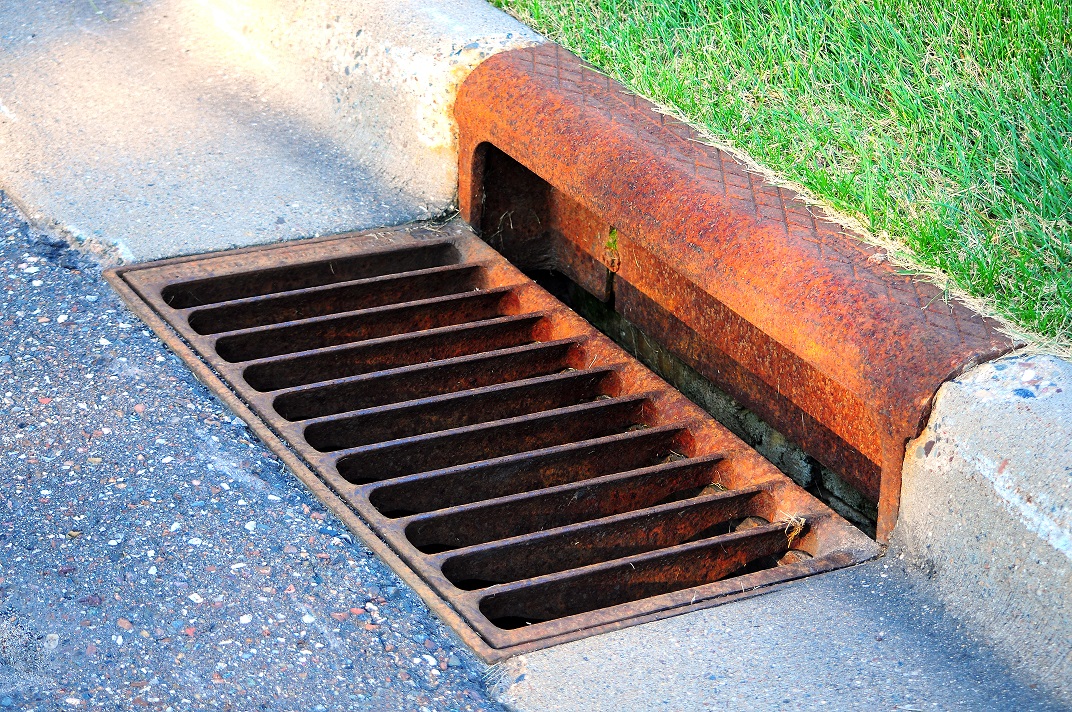 Old rusted sewer by lawn curb.